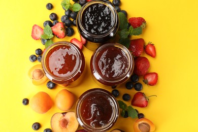 Photo of Different jams in jars and ingredients on yellow background, flat lay