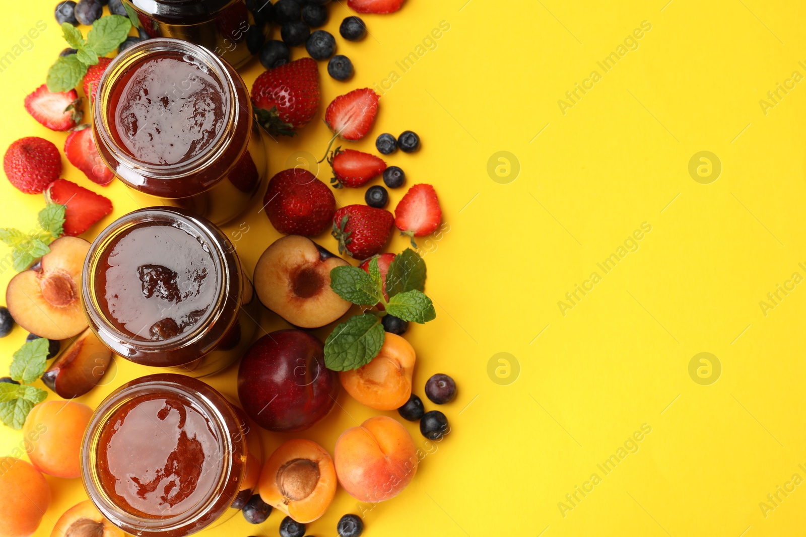 Different jams in jars and ingredients on yellow background, flat lay. Space for text Photo of Different jams in jars and ingredients on yellow background, flat lay. Space for text