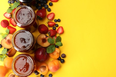 Photo of Different jams in jars and ingredients on yellow background, flat lay. Space for text