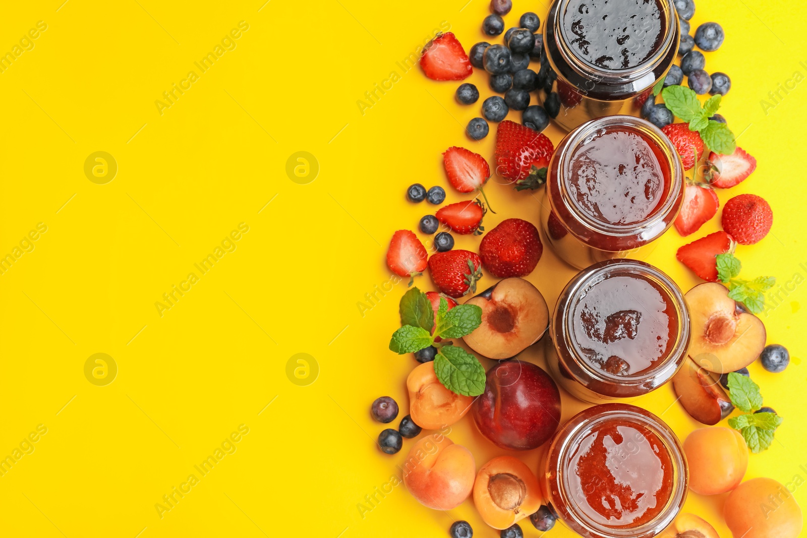 Different jams in jars and ingredients on yellow background, flat lay. Space for text Photo of Different jams in jars and ingredients on yellow background, flat lay. Space for text