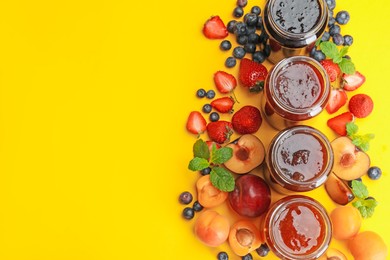 Photo of Different jams in jars and ingredients on yellow background, flat lay. Space for text