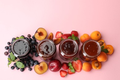 Photo of Different jams in jars and ingredients on light pink background, flat lay. Space for text