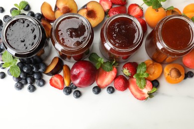 Photo of Different jams in jars and ingredients on white background, flat lay