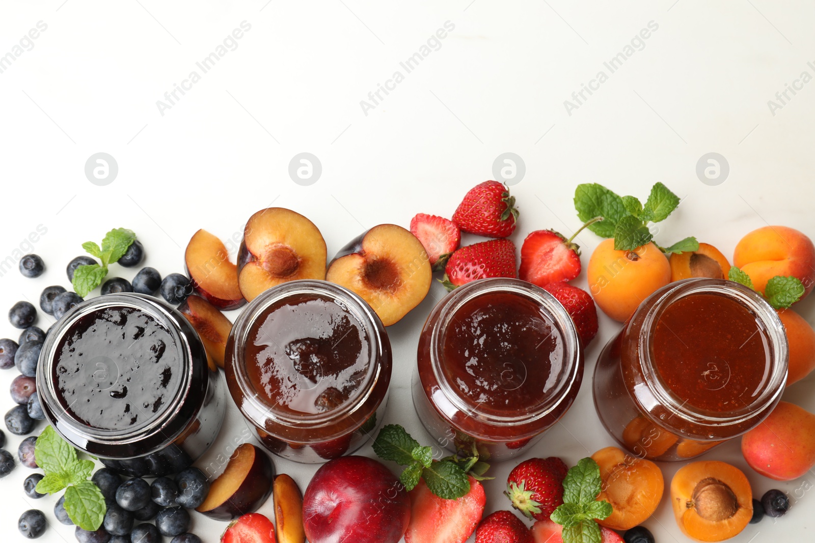 Different jams in jars and ingredients on white background, flat lay. Space for text Photo of Different jams in jars and ingredients on white background, flat lay. Space for text