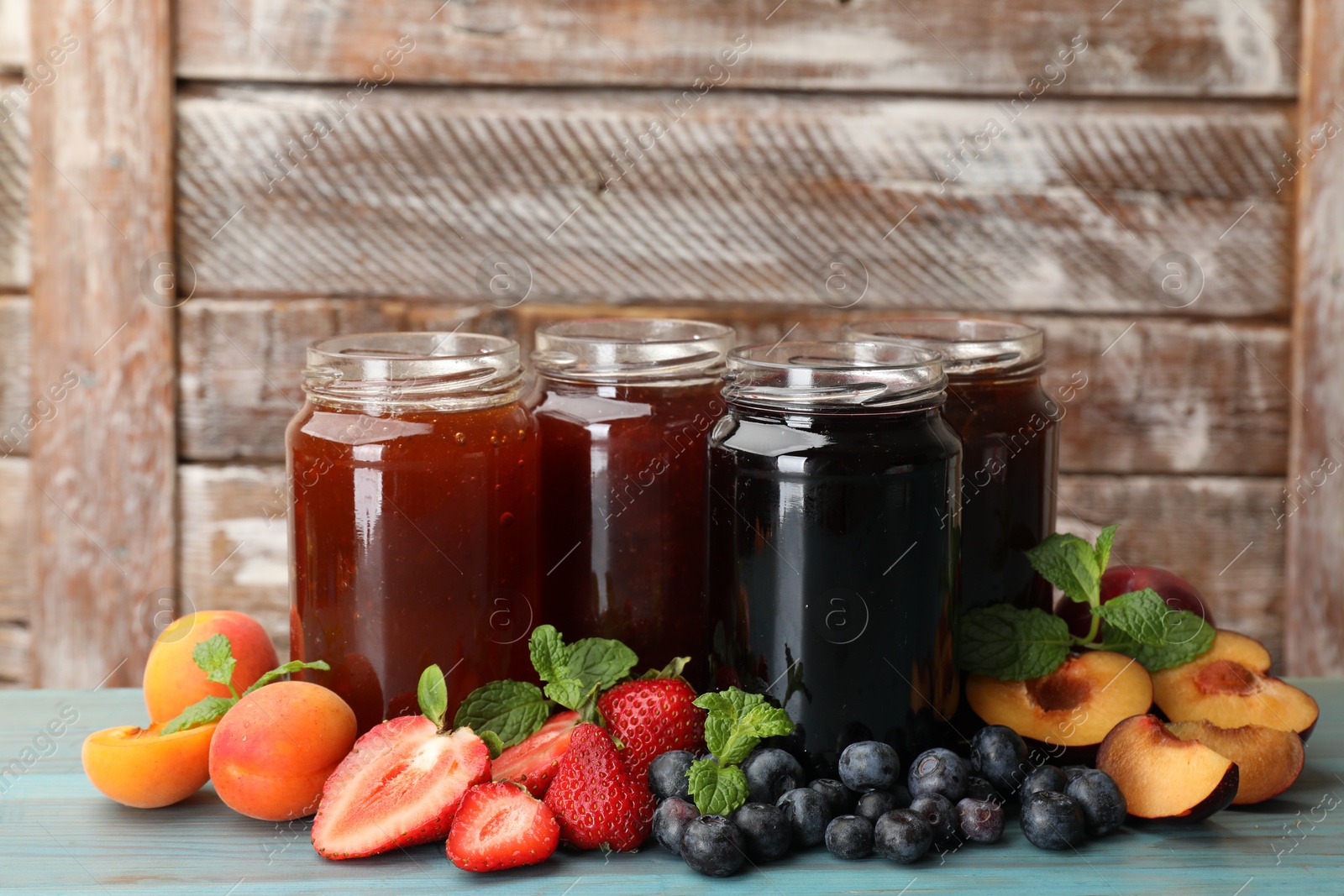 Different jams in jars and ingredients on blue wooden table. Space for text Photo of Different jams in jars and ingredients on blue wooden table. Space for text