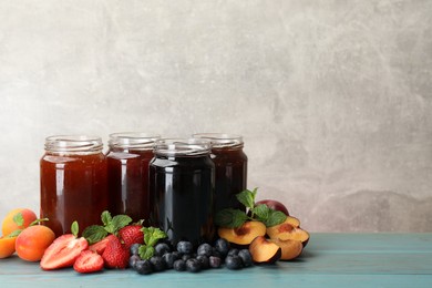 Photo of Different jams in jars and ingredients on blue wooden table. Space for text