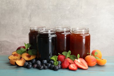 Photo of Different jams in jars and ingredients on blue wooden table. Space for text