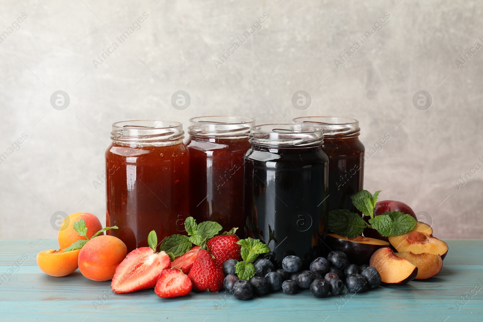 Different jams in jars and ingredients on blue wooden table. Space for text Photo of Different jams in jars and ingredients on blue wooden table. Space for text