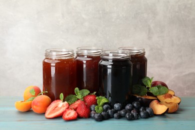 Photo of Different jams in jars and ingredients on blue wooden table. Space for text