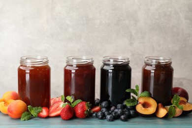 Photo of Different jams in jars and ingredients on blue wooden table. Space for text