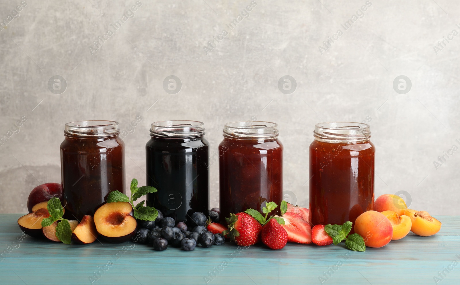 Different jams in jars and ingredients on blue wooden table. Space for text Photo of Different jams in jars and ingredients on blue wooden table. Space for text