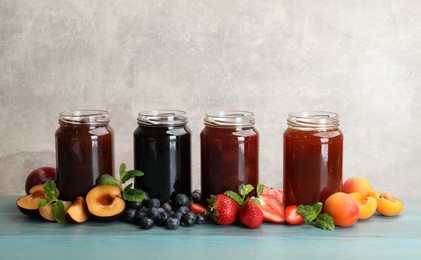 Photo of Different jams in jars and ingredients on blue wooden table. Space for text