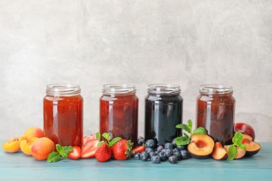 Photo of Different jams in jars and ingredients on blue wooden table. Space for text