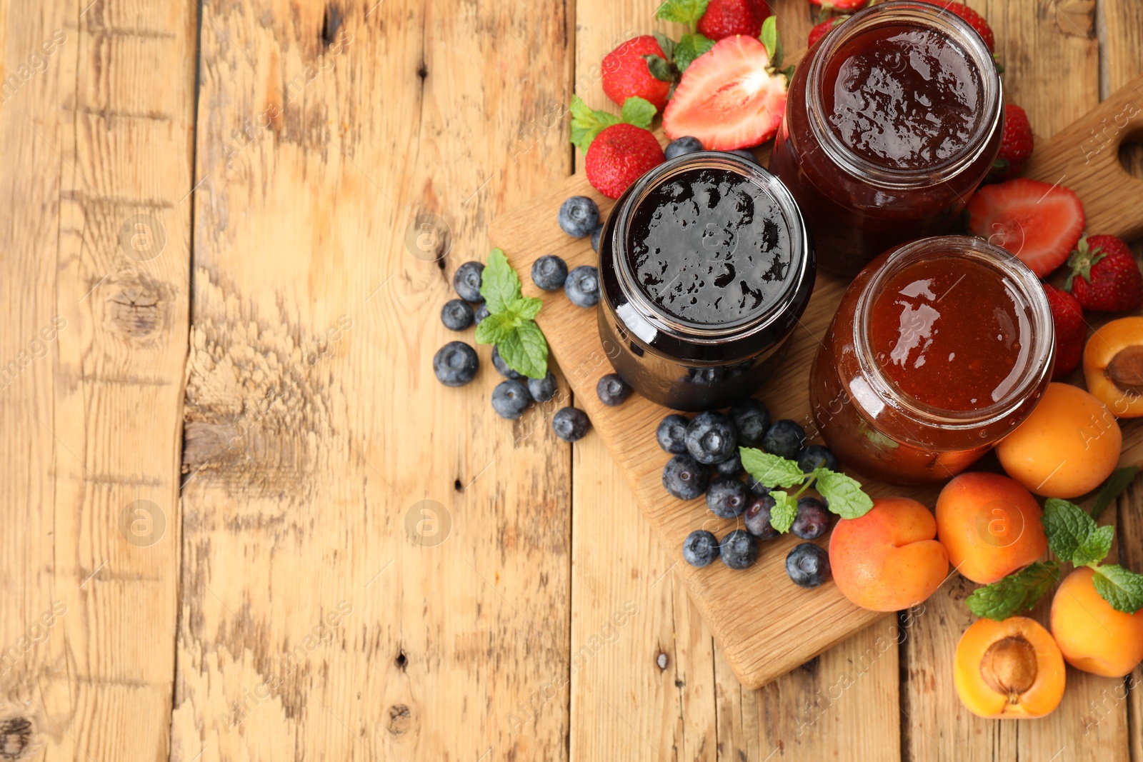 Different jams in jars and ingredients on wooden table, flat lay. Space for text Photo of Different jams in jars and ingredients on wooden table, flat lay. Space for text