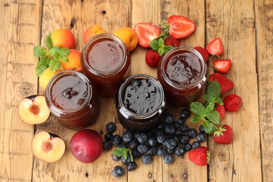 Photo of Different jams in jars and ingredients on wooden table, flat lay