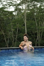 Photo of Happy woman relaxing in swimming pool outdoors