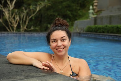 Photo of Happy woman relaxing in swimming pool outdoors