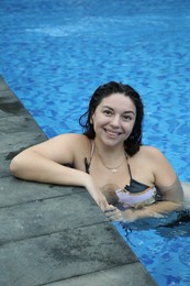 Photo of Happy woman relaxing in swimming pool outdoors