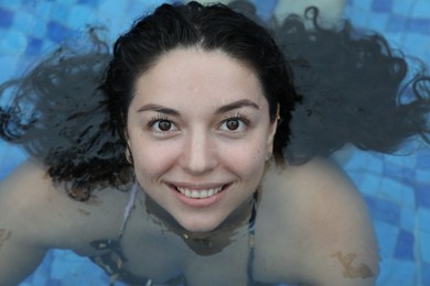 Photo of Happy woman relaxing in swimming pool outdoors, above view