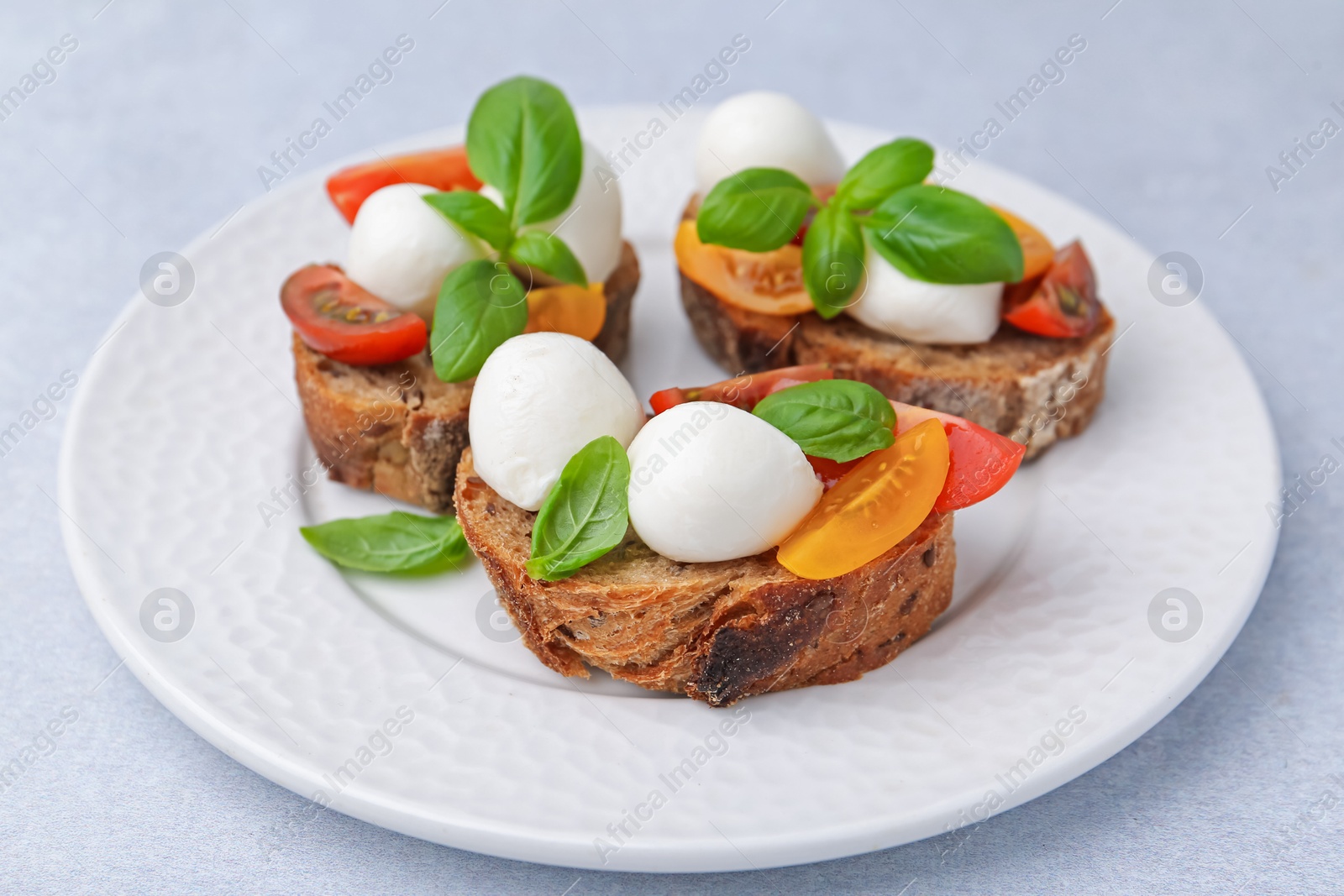 Tasty sandwiches with mozzarella cheese, tomatoes and basil on white table, closeup Photo of Tasty sandwiches with mozzarella cheese, tomatoes and basil on white table, closeup