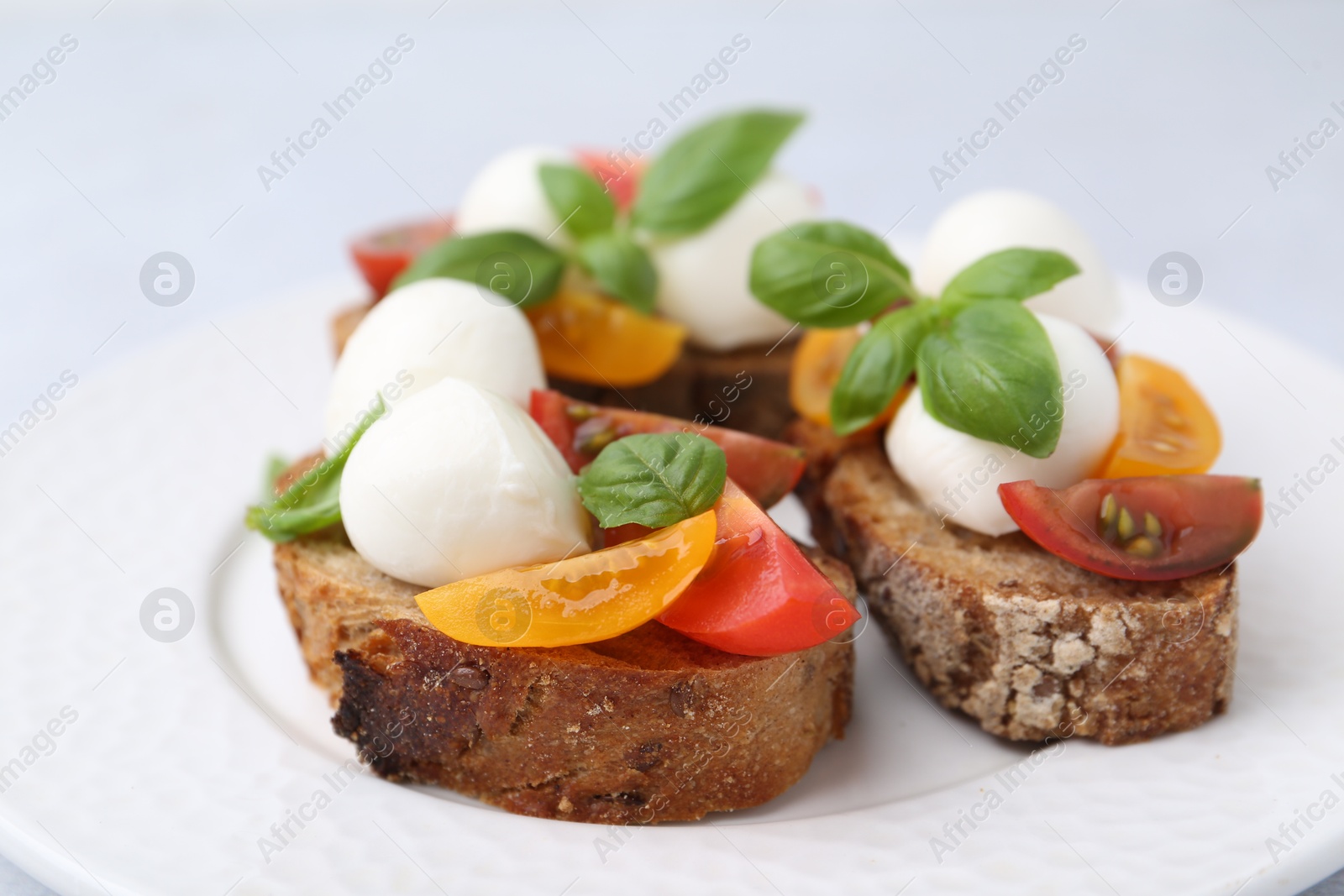 Tasty sandwiches with mozzarella cheese, tomatoes and basil on white table, closeup Photo of Tasty sandwiches with mozzarella cheese, tomatoes and basil on white table, closeup