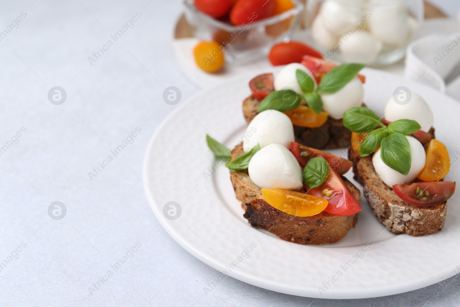 Tasty sandwiches with mozzarella cheese, tomatoes and basil on white table, closeup. Space for text Photo of Tasty sandwiches with mozzarella cheese, tomatoes and basil on white table, closeup. Space for text