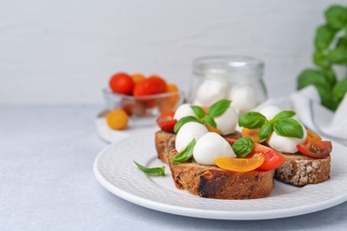 Photo of Tasty sandwiches with mozzarella cheese, tomatoes and basil on white table. Space for text
