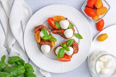Photo of Tasty sandwiches with mozzarella cheese, tomatoes and basil on white table, flat lay
