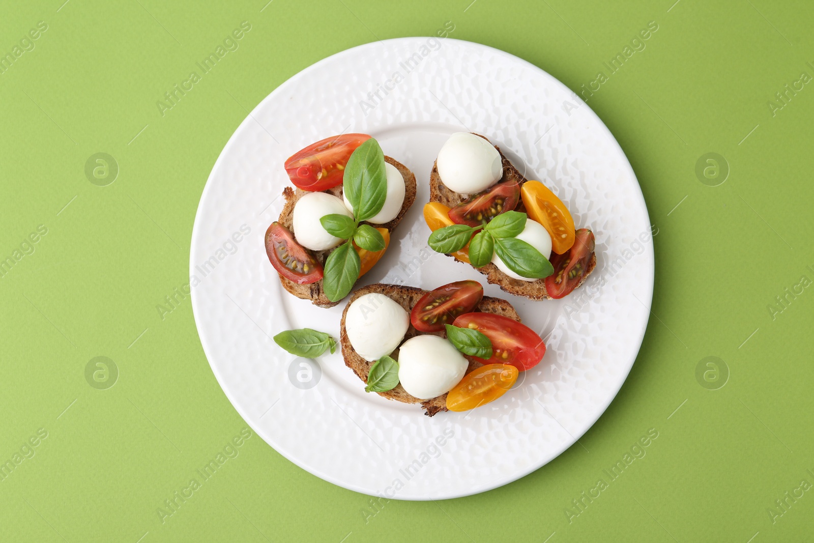 Tasty sandwiches with mozzarella cheese, tomatoes and basil on green background, top view Photo of Tasty sandwiches with mozzarella cheese, tomatoes and basil on green background, top view