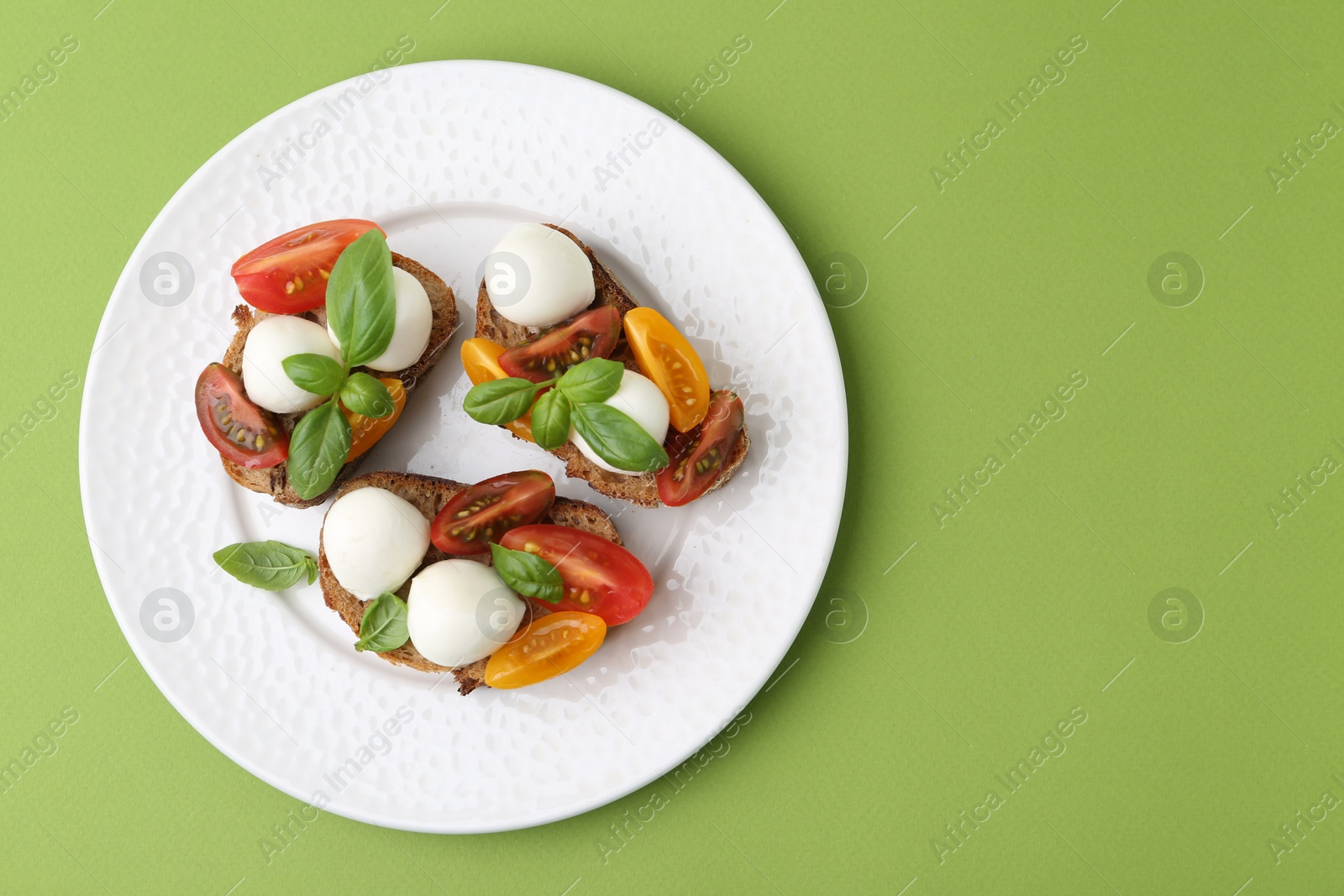 Tasty sandwiches with mozzarella cheese, tomatoes and basil on green background, top view. Space for text Photo of Tasty sandwiches with mozzarella cheese, tomatoes and basil on green background, top view. Space for text