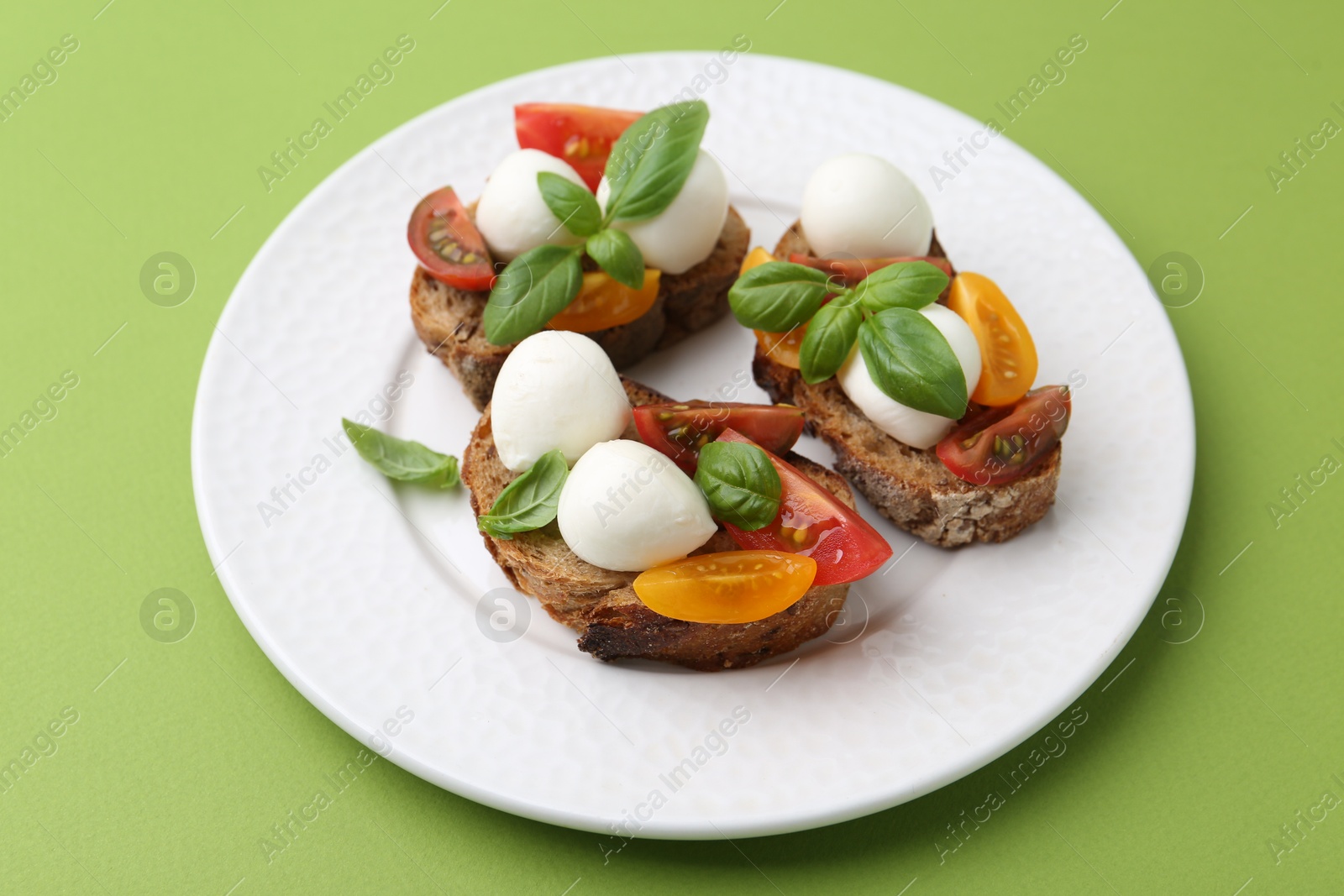 Tasty sandwiches with mozzarella cheese, tomatoes and basil on green background, closeup Photo of Tasty sandwiches with mozzarella cheese, tomatoes and basil on green background, closeup