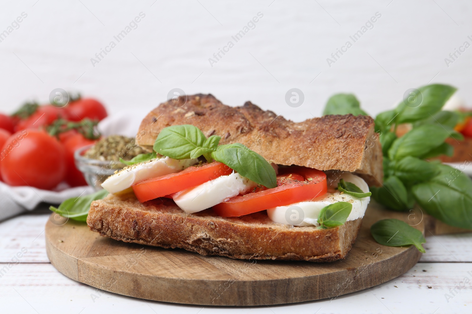 Tasty sandwich with mozzarella cheese, tomatoes and basil on white wooden table, closeup Photo of Tasty sandwich with mozzarella cheese, tomatoes and basil on white wooden table, closeup