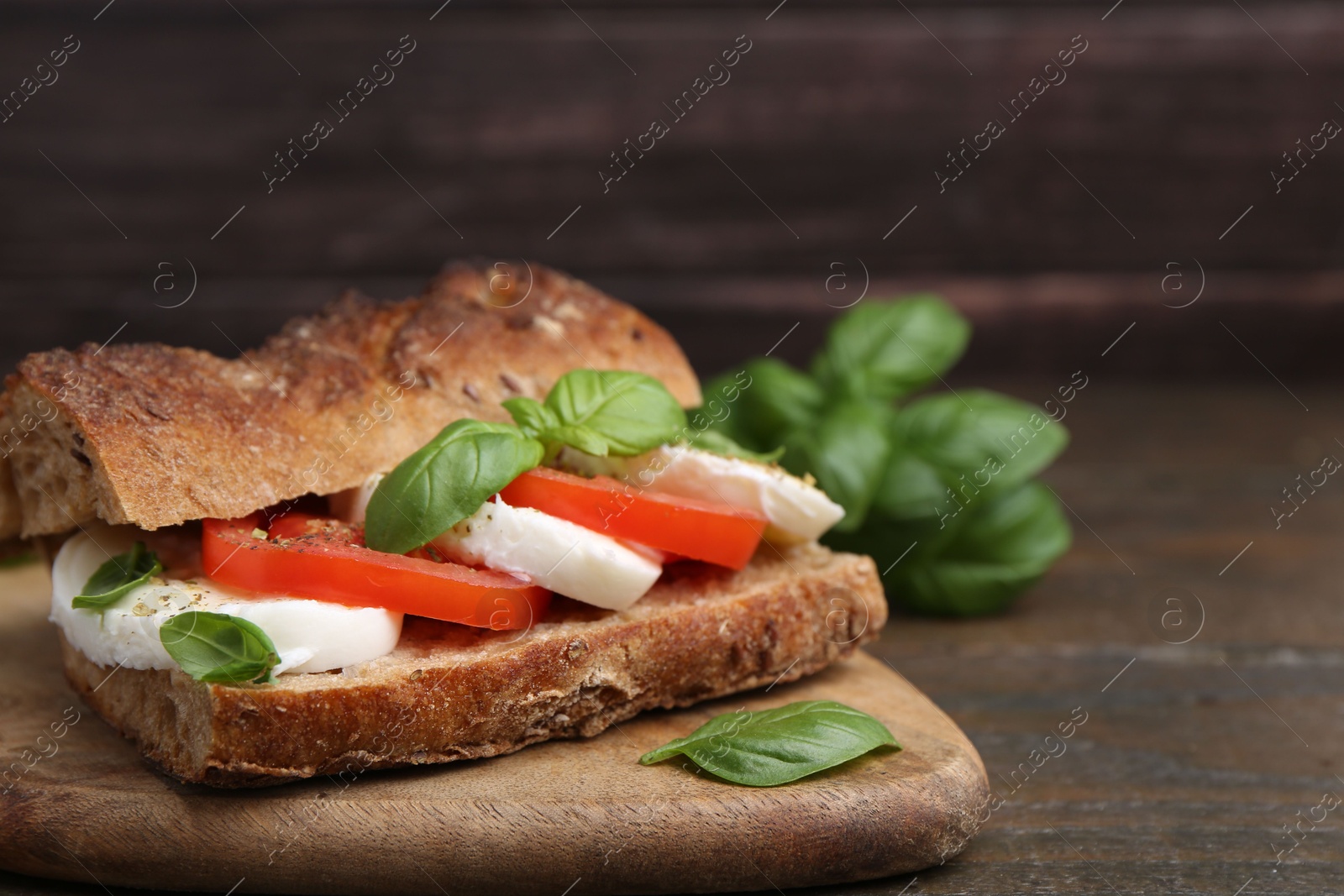 Tasty sandwich with mozzarella cheese, tomatoes and basil on wooden table, closeup. Space for text Photo of Tasty sandwich with mozzarella cheese, tomatoes and basil on wooden table, closeup. Space for text