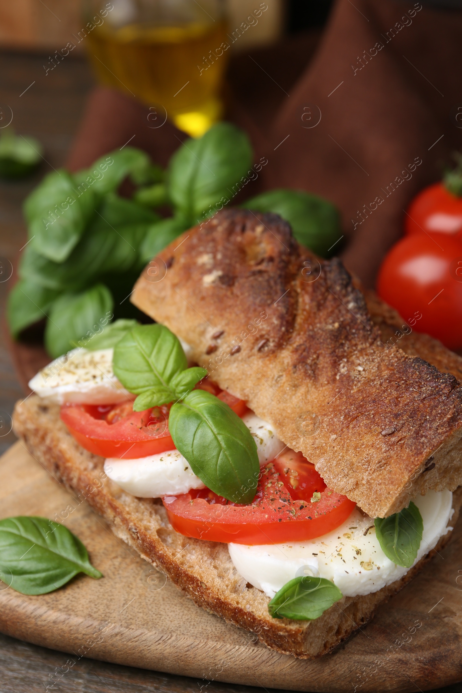Tasty sandwich with mozzarella cheese, tomatoes and basil on wooden table, closeup Photo of Tasty sandwich with mozzarella cheese, tomatoes and basil on wooden table, closeup