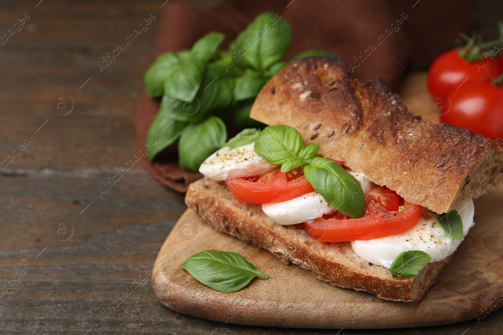 Tasty sandwich with mozzarella cheese, tomatoes and basil on wooden table, closeup. Space for text Photo of Tasty sandwich with mozzarella cheese, tomatoes and basil on wooden table, closeup. Space for text