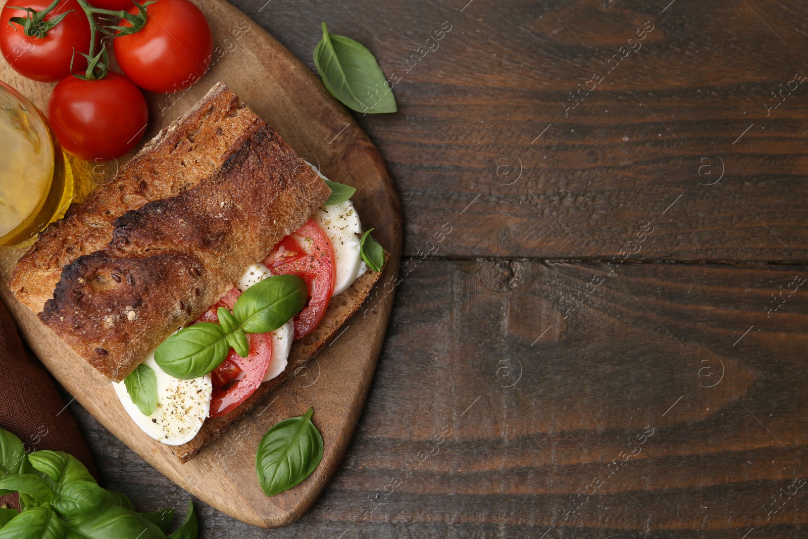 Tasty sandwich with mozzarella cheese, tomatoes and basil on wooden table, flat lay. Space for text Photo of Tasty sandwich with mozzarella cheese, tomatoes and basil on wooden table, flat lay. Space for text