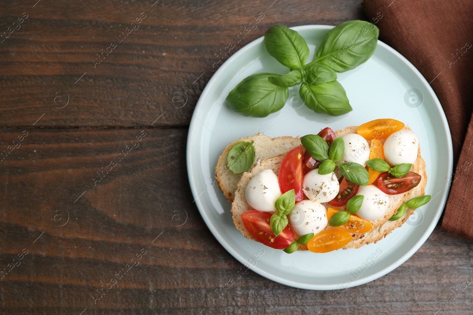 Tasty sandwich with mozzarella cheese, tomatoes and basil on wooden table, top view. Space for text Photo of Tasty sandwich with mozzarella cheese, tomatoes and basil on wooden table, top view. Space for text