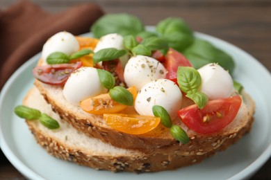 Photo of Tasty sandwich with mozzarella cheese, tomatoes and basil on wooden table, closeup