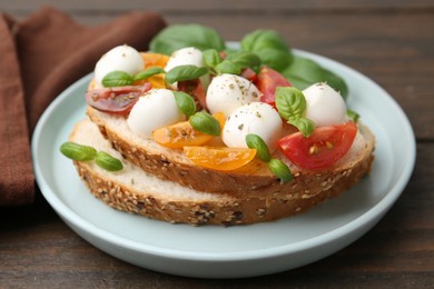 Photo of Tasty sandwich with mozzarella cheese, tomatoes and basil on wooden table, closeup