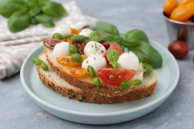 Photo of Tasty sandwich with mozzarella cheese, tomatoes and basil on grey table, closeup