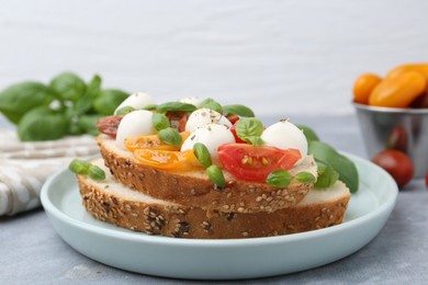 Photo of Tasty sandwich with mozzarella cheese, tomatoes and basil on grey table, closeup
