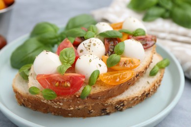 Photo of Tasty sandwich with mozzarella cheese, tomatoes and basil on grey table, closeup