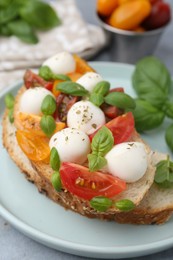 Photo of Tasty sandwich with mozzarella cheese, tomatoes and basil on grey table, closeup