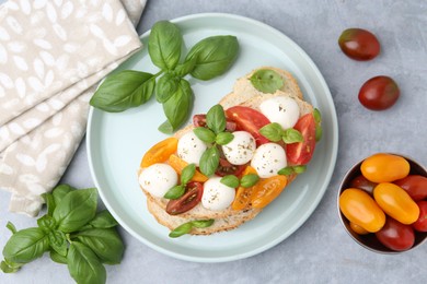 Photo of Tasty sandwich with mozzarella cheese, tomatoes and basil on grey table, flat lay