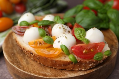 Photo of Tasty sandwich with mozzarella cheese, tomatoes and basil on brown table, closeup