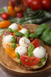 Photo of Tasty sandwich with mozzarella cheese, tomatoes and basil on brown table, closeup