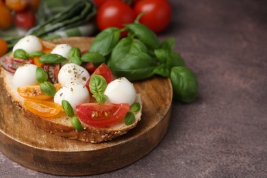 Photo of Tasty sandwich with mozzarella cheese, tomatoes and basil on brown table, closeup