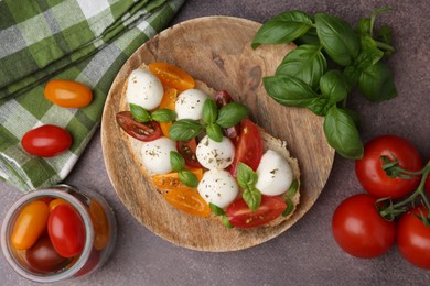 Photo of Tasty sandwich with mozzarella cheese, tomatoes and basil on brown table, flat lay
