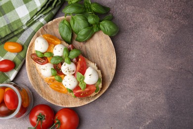 Photo of Tasty sandwich with mozzarella cheese, tomatoes and basil on brown table, flat lay. Space for text