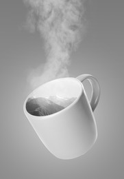 Image of Mountain landscape in cup on grey gradient background. Steam rising out of cup